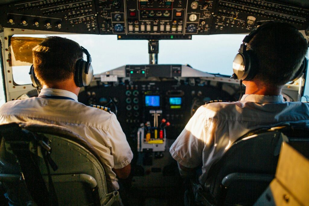 Two pilots in cockpit navigating airplane at high altitude, daylight