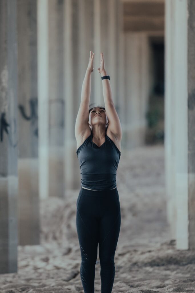 woman in blue tank top and black leggings doing yoga