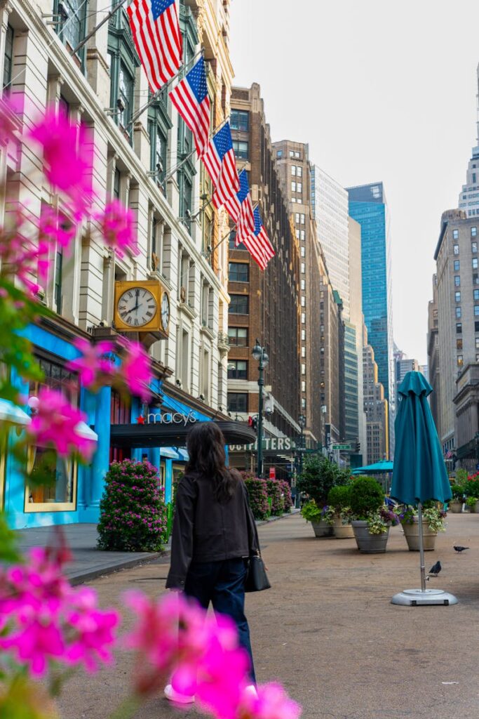 Street scene in New York City with colorful flowers and American flags.