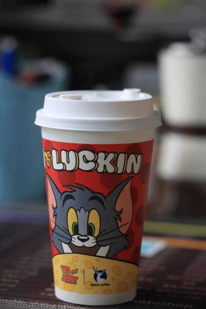 Vibrant coffee cup featuring Tom and Jerry from Luckin Coffee on a blurred background.