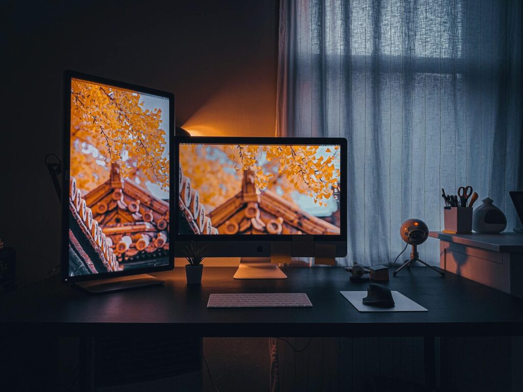 Cozy home office setup with dual monitors displaying autumn scenery.