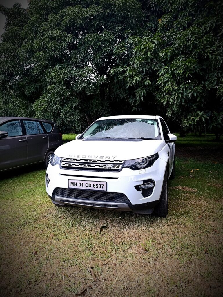 a white car parked in a grassy area with trees in the background