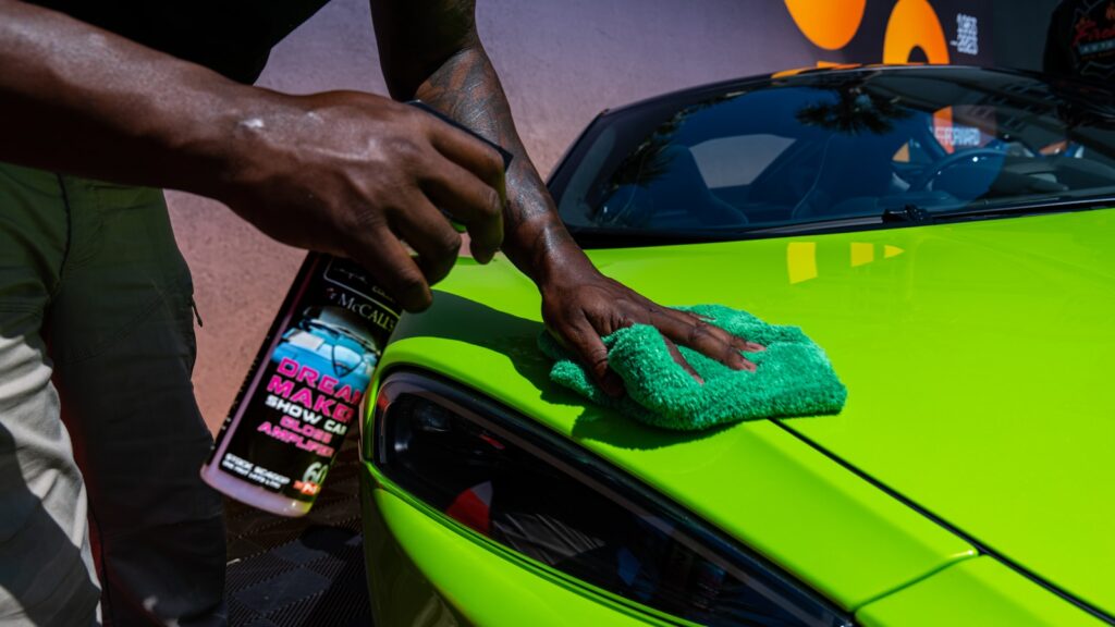 a man cleaning a green car with a micro micro cloth