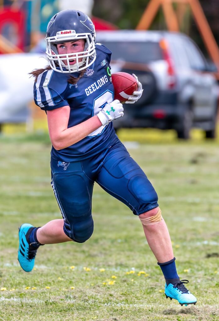 woman in blue football jersey holding football