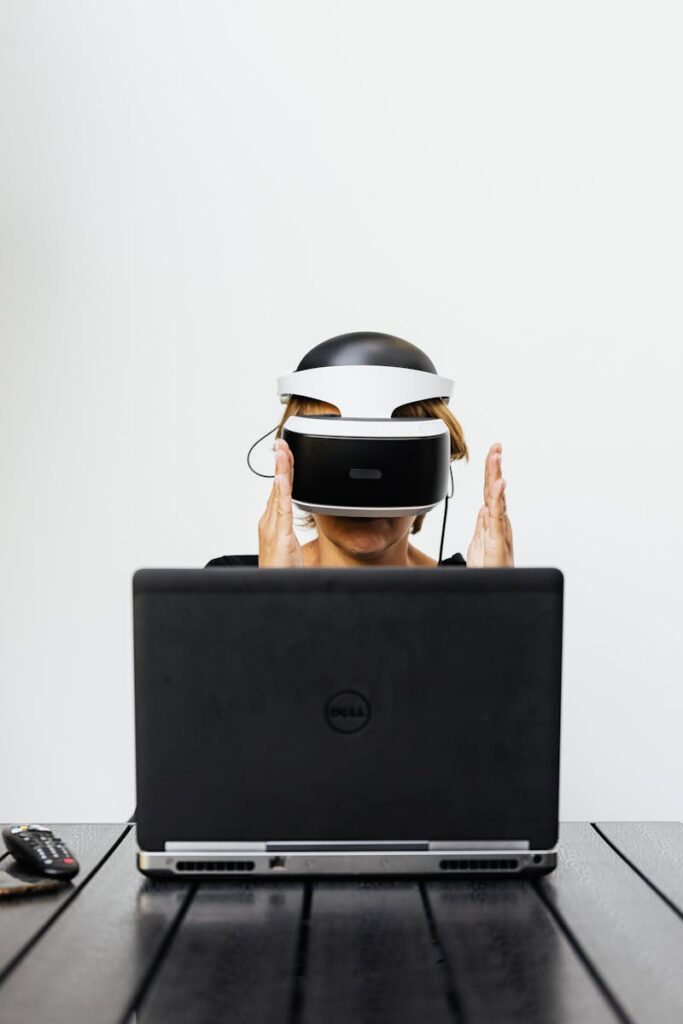 Adult using VR headset and laptop for virtual reality experience indoors.