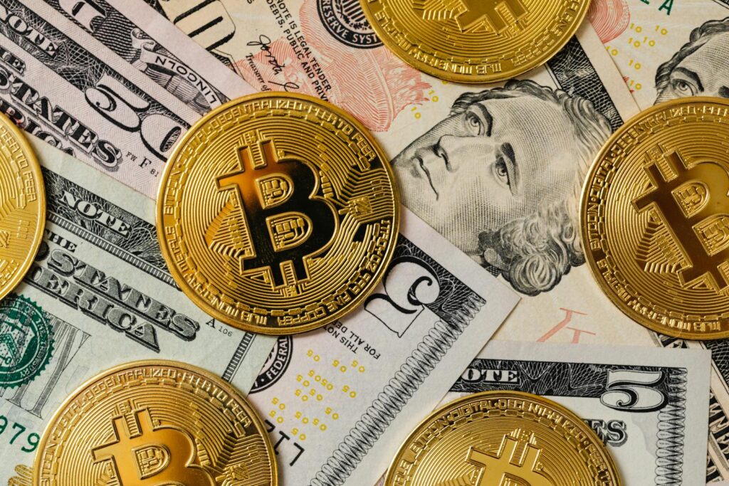 Golden bitcoins on a background of US dollar bills representing cryptocurrency and traditional money.