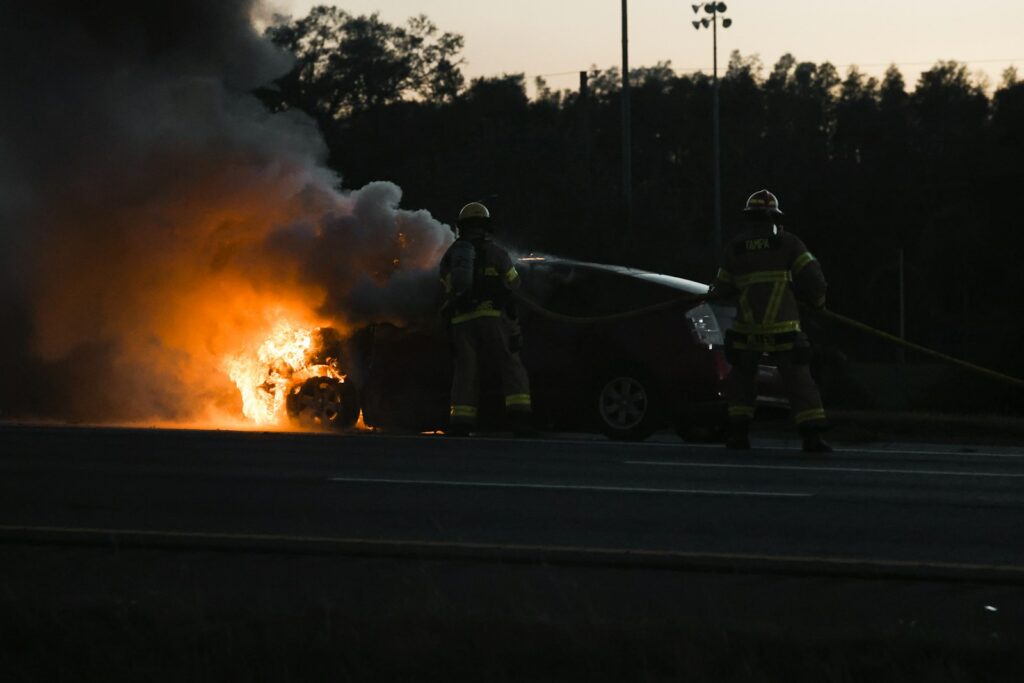 Two firemen are putting out a car fire