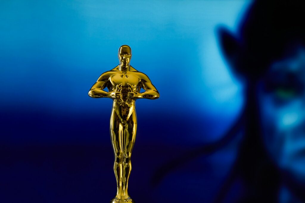 a golden statue of an oscar standing in front of a blue background