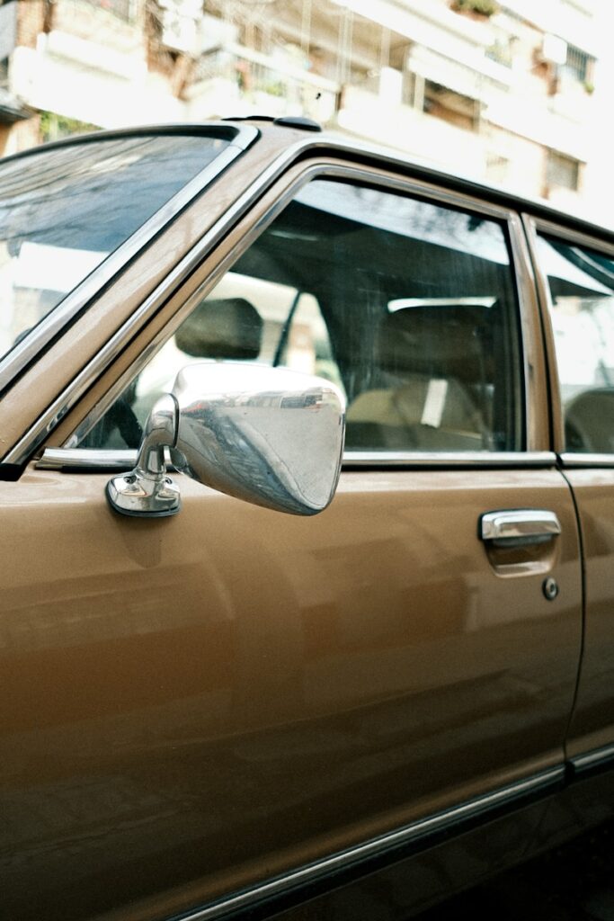 An old brown car is parked outside.