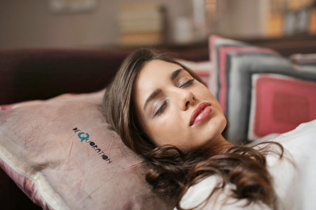A woman peacefully sleeping indoors on a pillow, exuding comfort and relaxation.