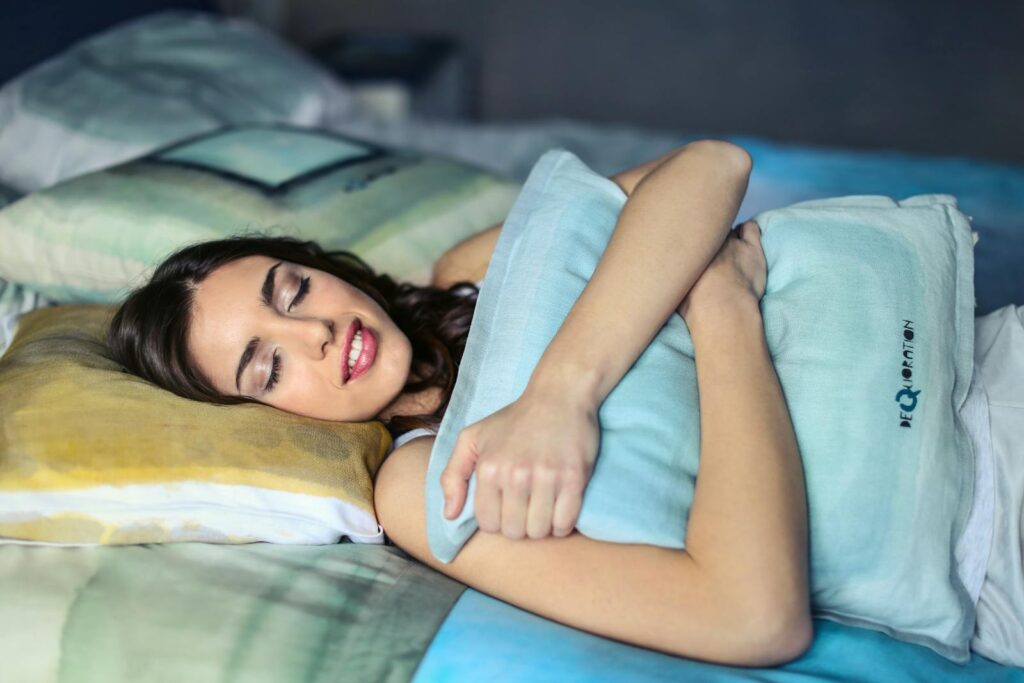 A woman sleeping peacefully in bed hugging a soft pillow, evoking comfort and relaxation.