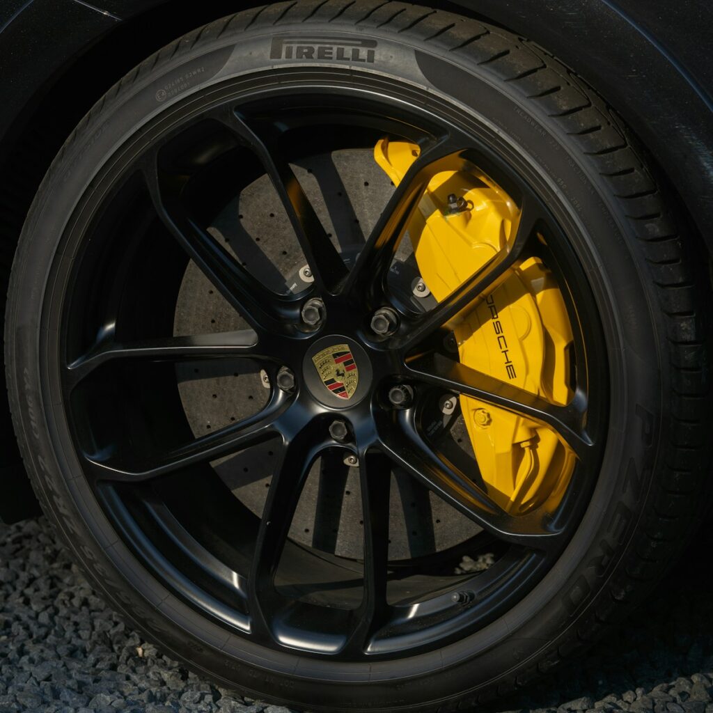 Black porsche wheel with bright yellow brake calipers.