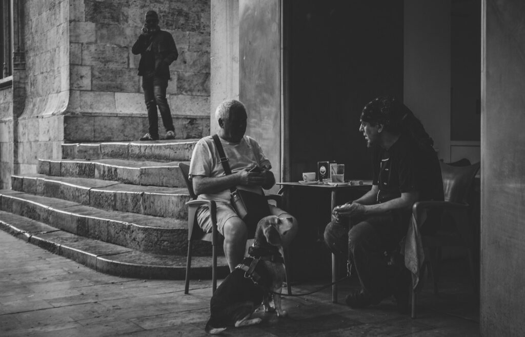 two men sitting outside building in grayscale photo