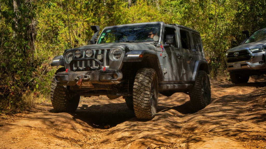 a couple of jeeps driving down a dirt road