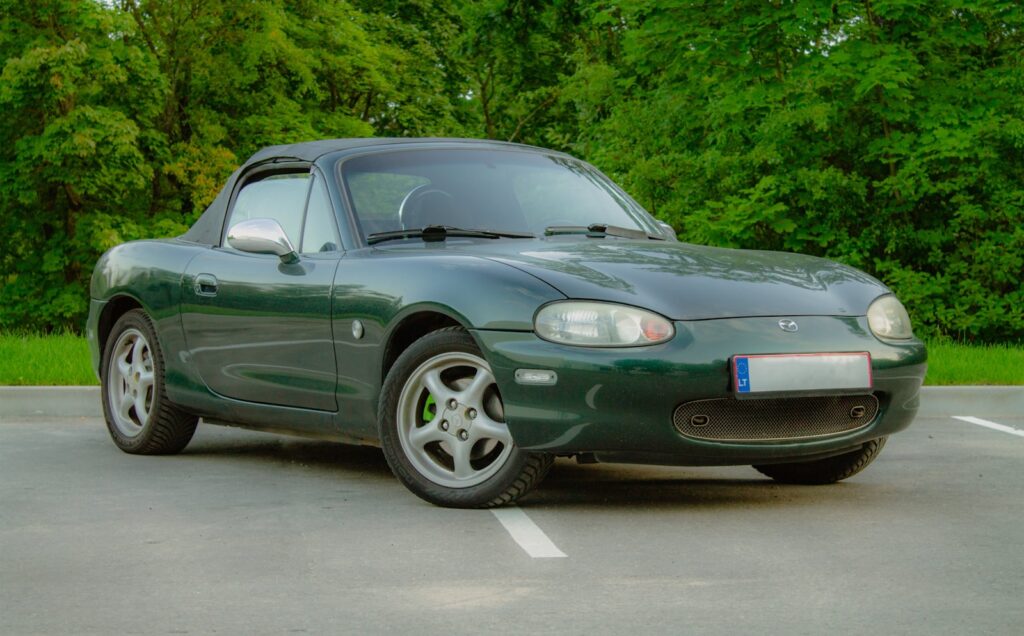 Dark green convertible sports car parked outdoors.