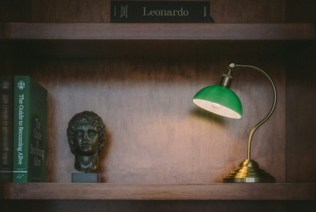 A green lamp lights books on a bookshelf.