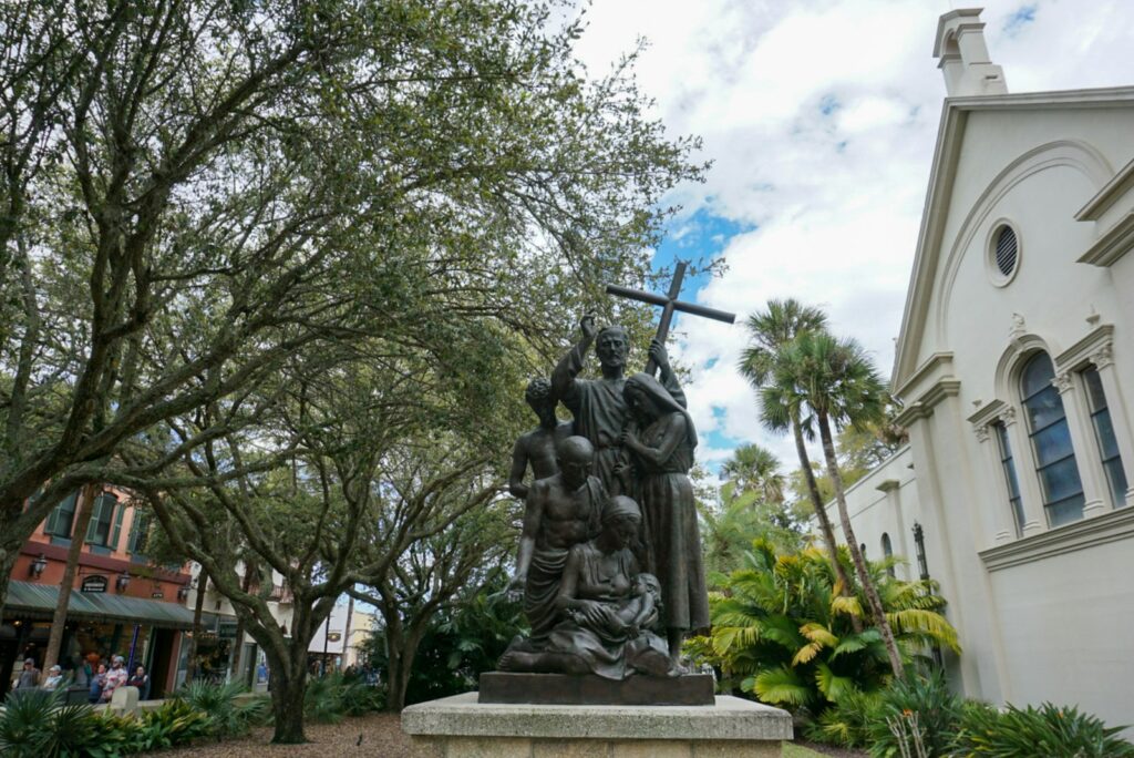 a statue of a man holding a cross in front of a building