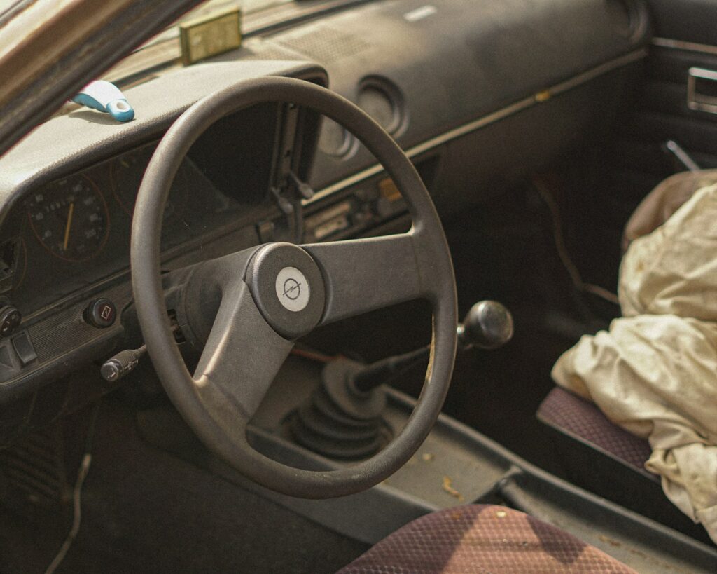 Interior of an old car with steering wheel and gearshift.