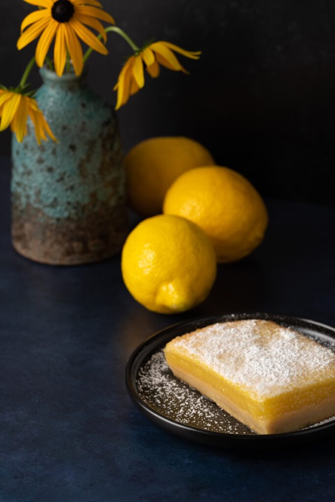 a plate of lemons and a vase of flowers