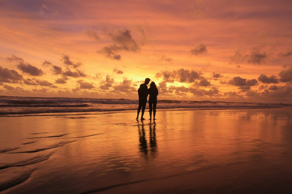 a couple of people standing on top of a beach