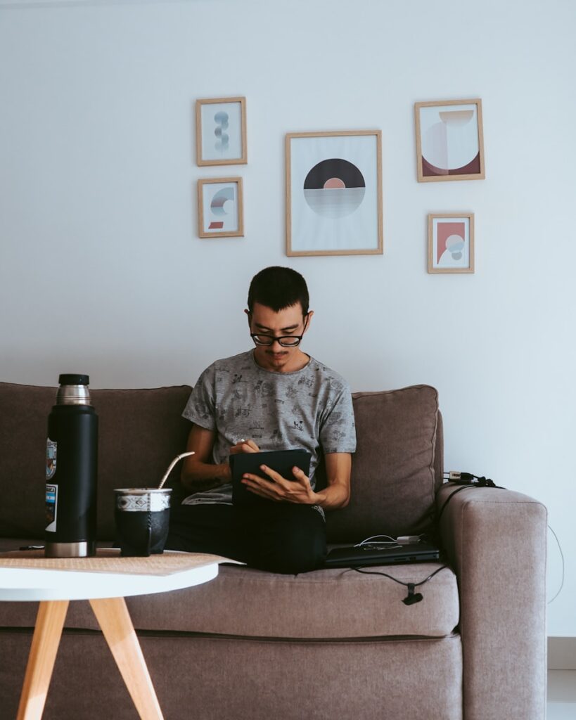 a man sitting on a couch using a tablet