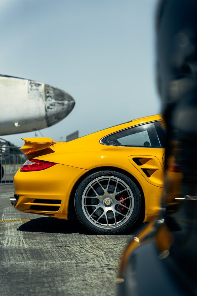 A yellow sports car parked in front of an airplane