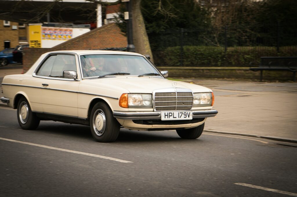 A white car driving down a street next to a building
