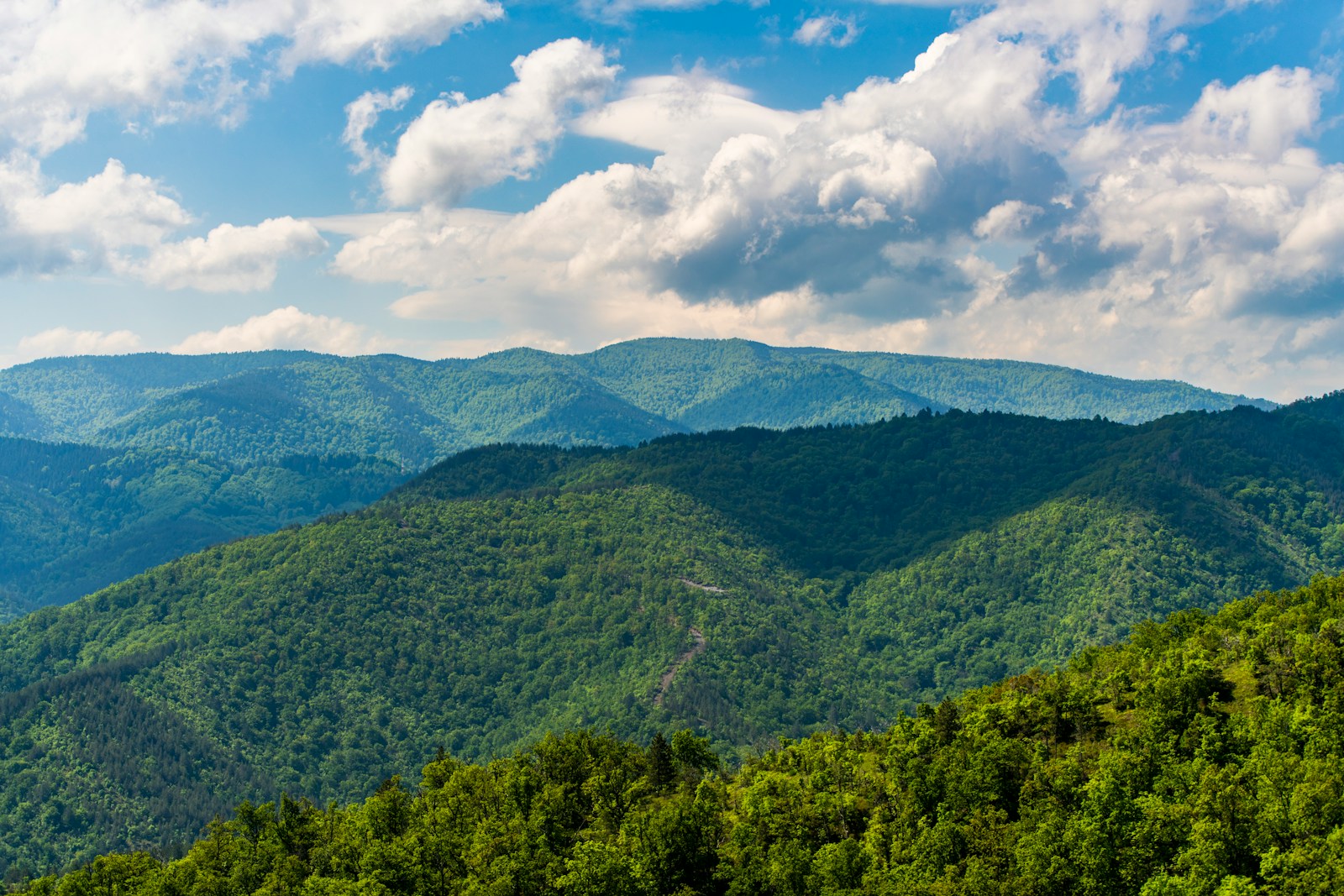 A scenic view of a mountain range with clouds in the sky