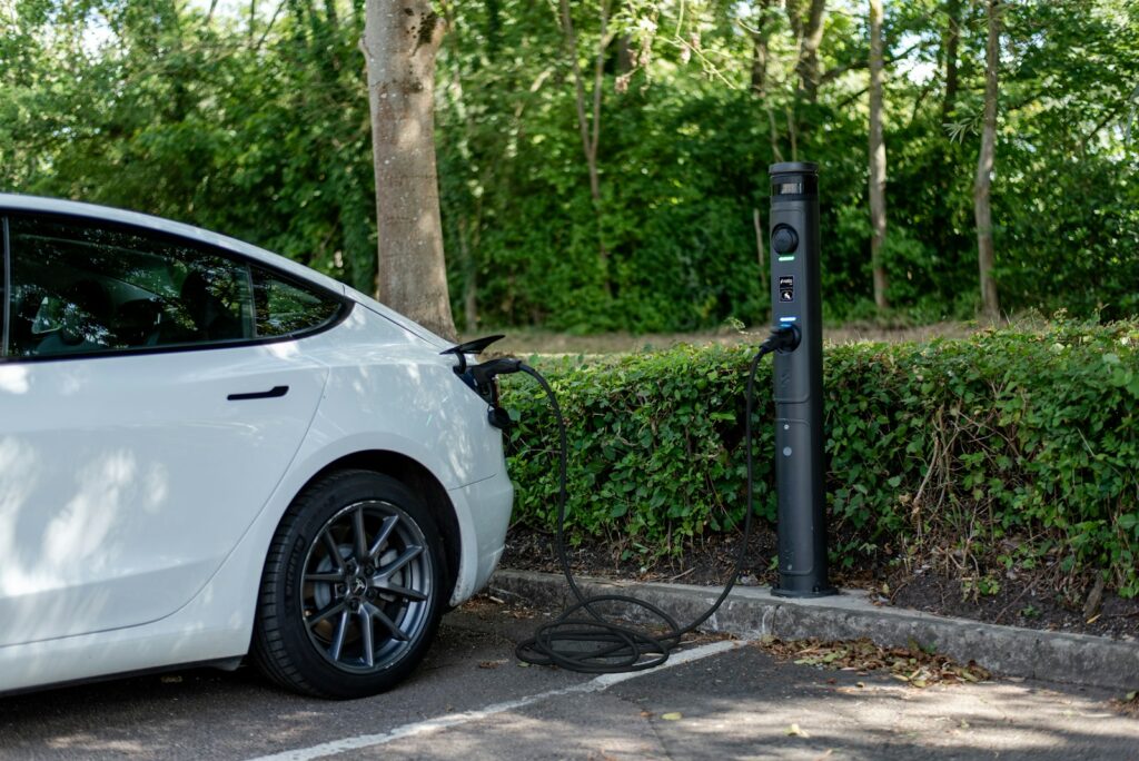 White electric car plugged in at a charging station.