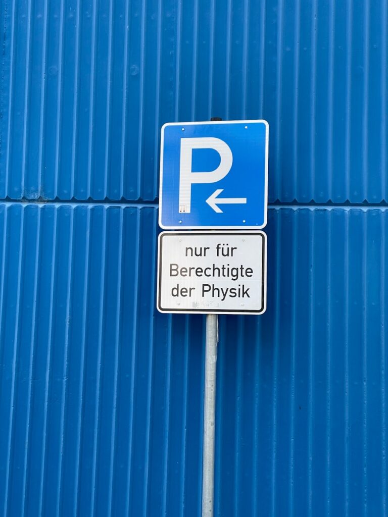 a parking sign on a pole in front of a blue wall