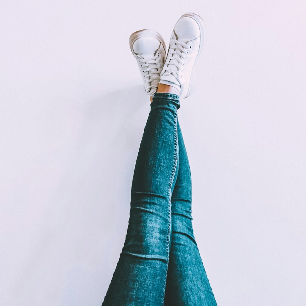 person in blue denim jeans and white sneakers