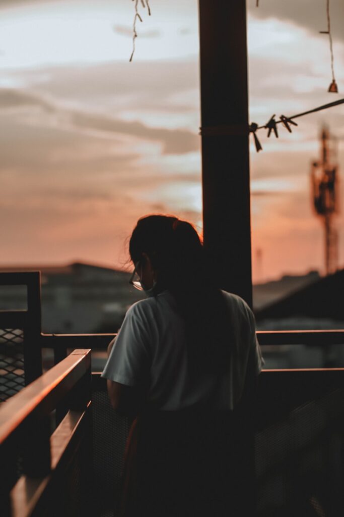 a woman standing in front of a window at sunset