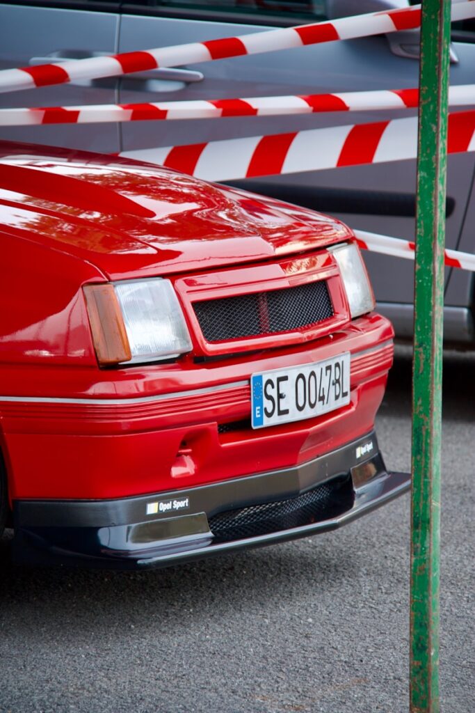 a red car parked next to a green pole