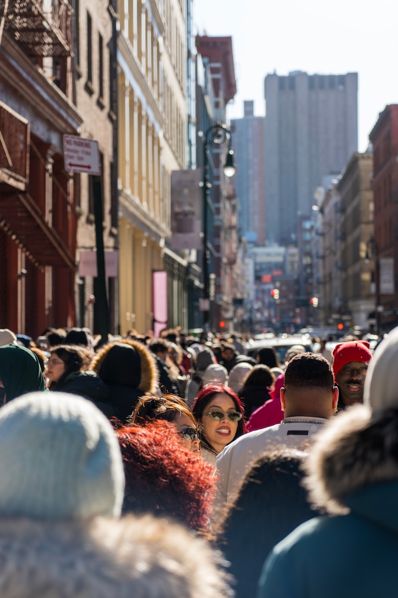 A crowd of people walking down a street next to tall buildings