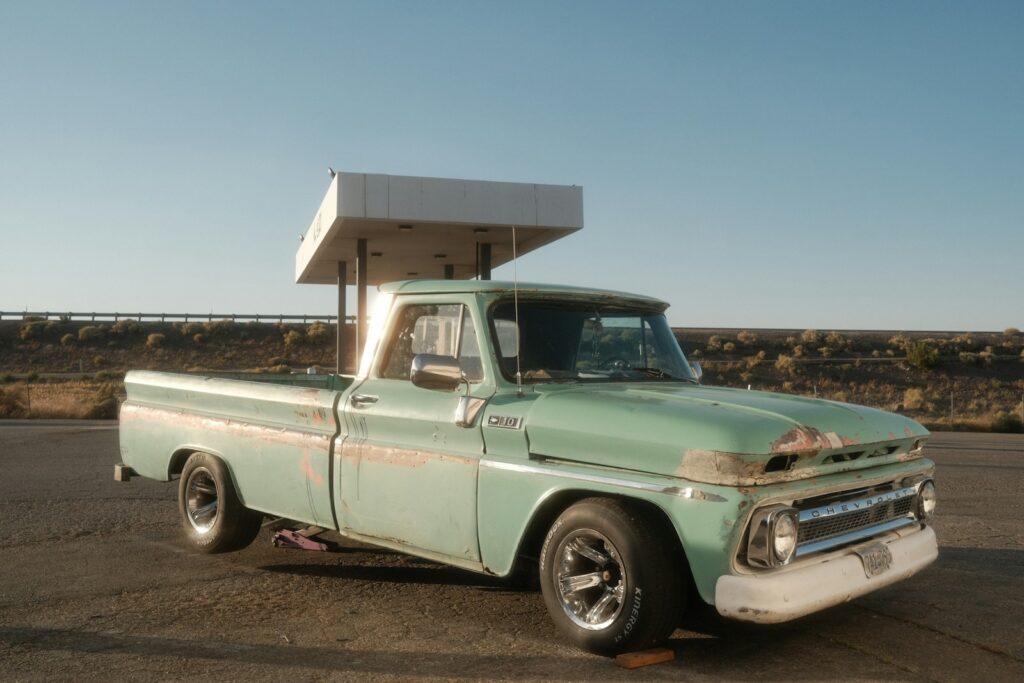 an old green truck parked in a parking lot
