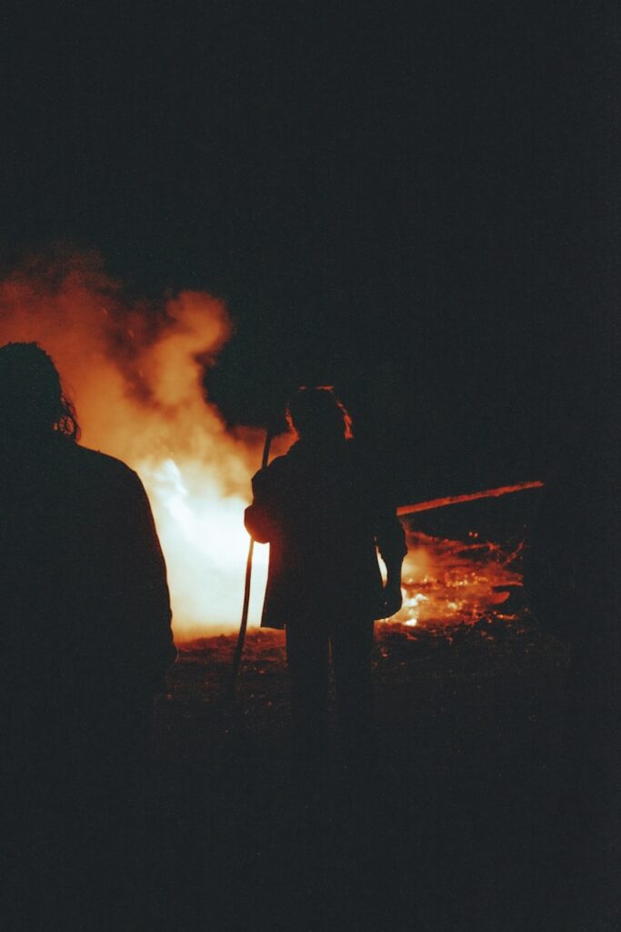a couple of people standing next to a fire