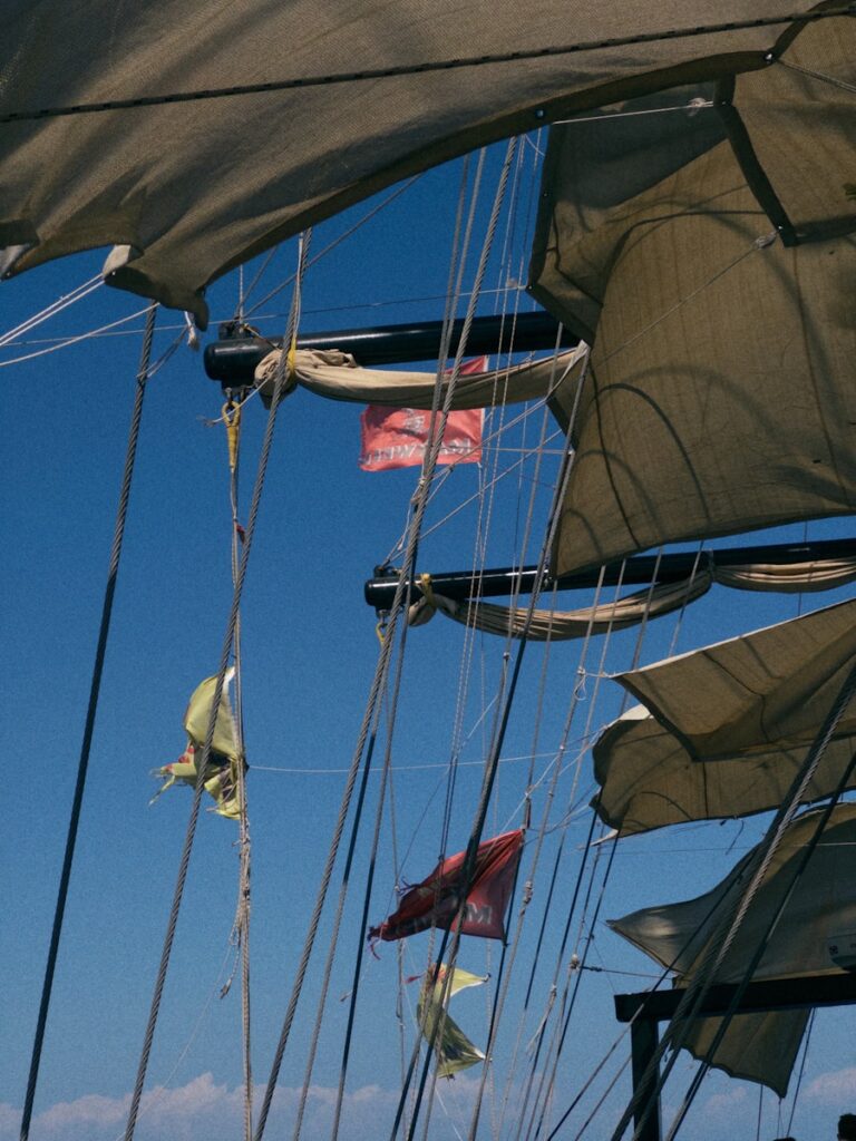 Sailboat sails and flags billow in the wind.