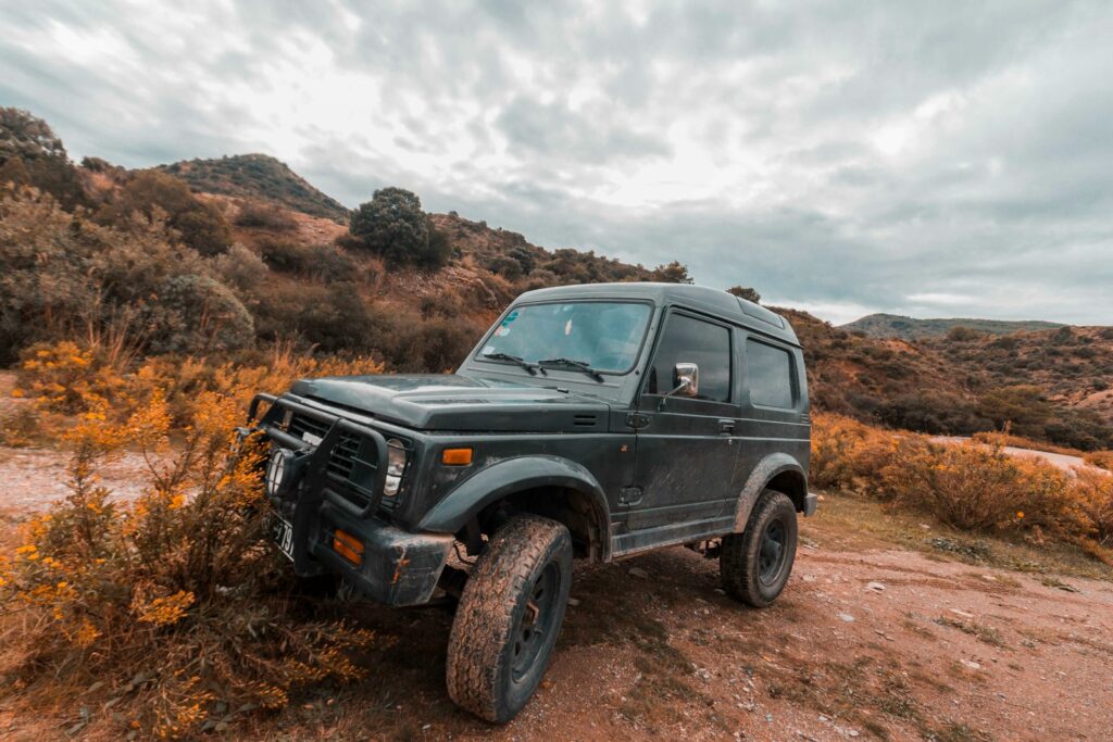 parked black SUV on dirt and plant field