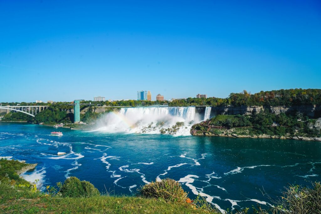 a waterfall with a bridge and a city in the background