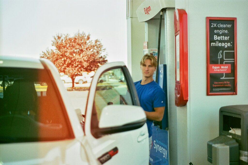 a man standing in a gas station next to a white car