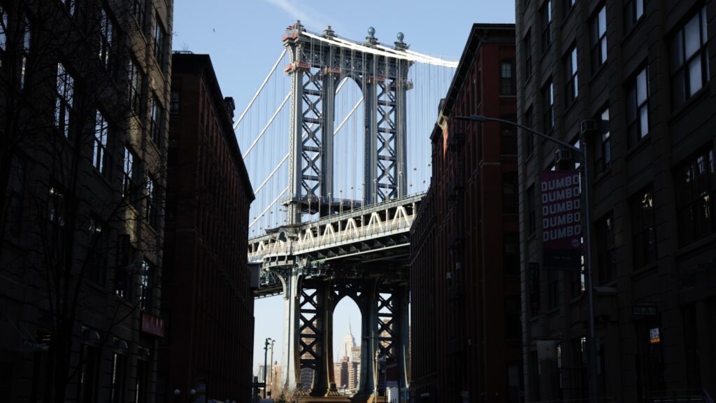 a tall bridge over a city street next to tall buildings