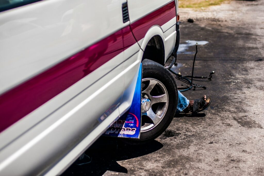 a man sitting on the ground next to a parked car