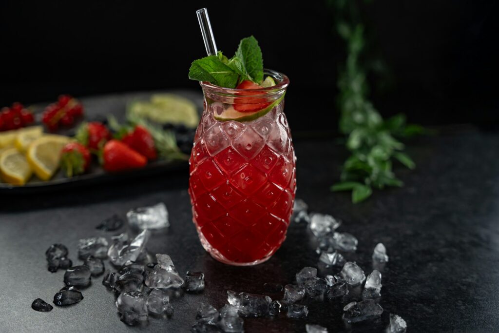 a glass filled with a drink next to a plate of fruit