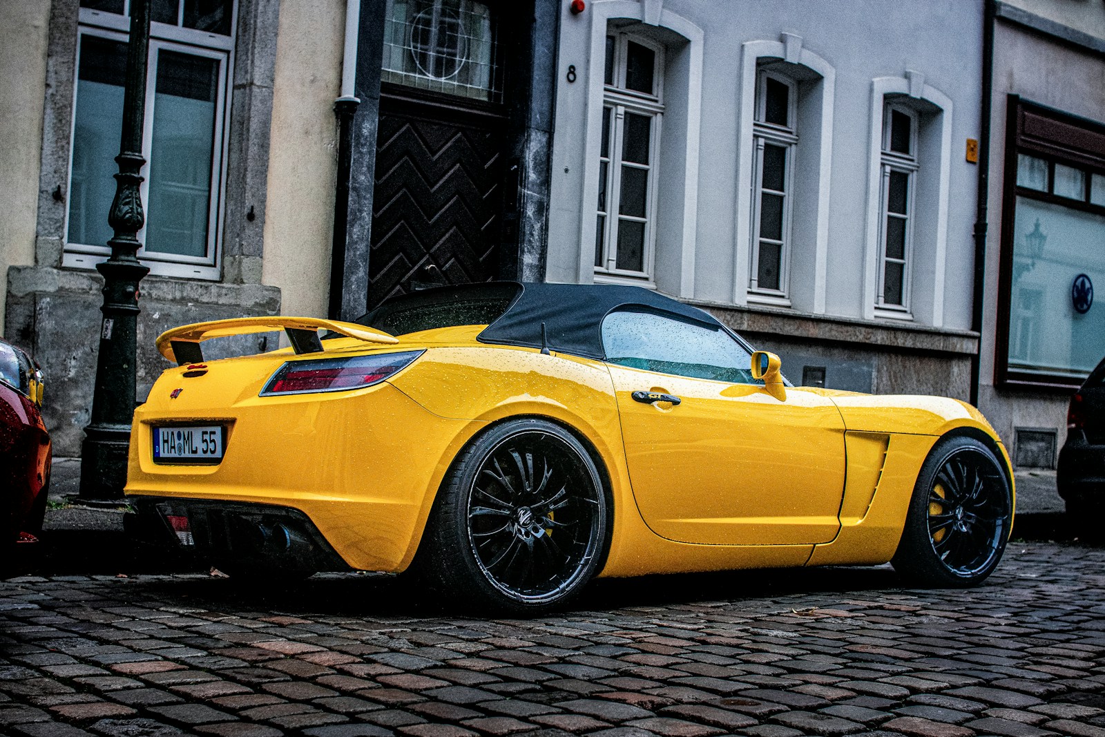 A yellow sports car parked on a cobblestone street