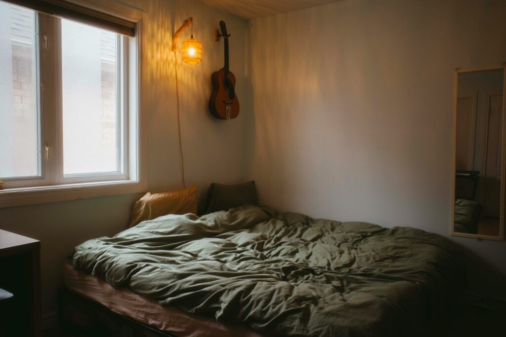 A cozy bedroom with a guitar and bed.