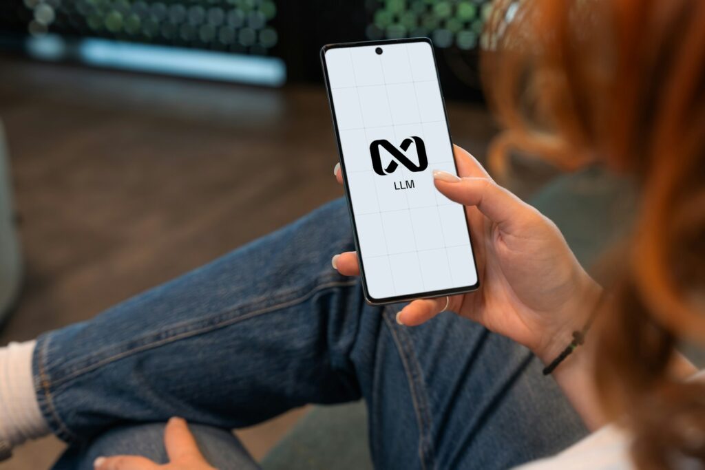 Person holding a smartphone with a logo on screen.