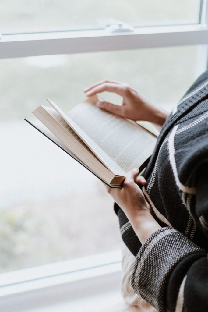 A person reading a book by a window