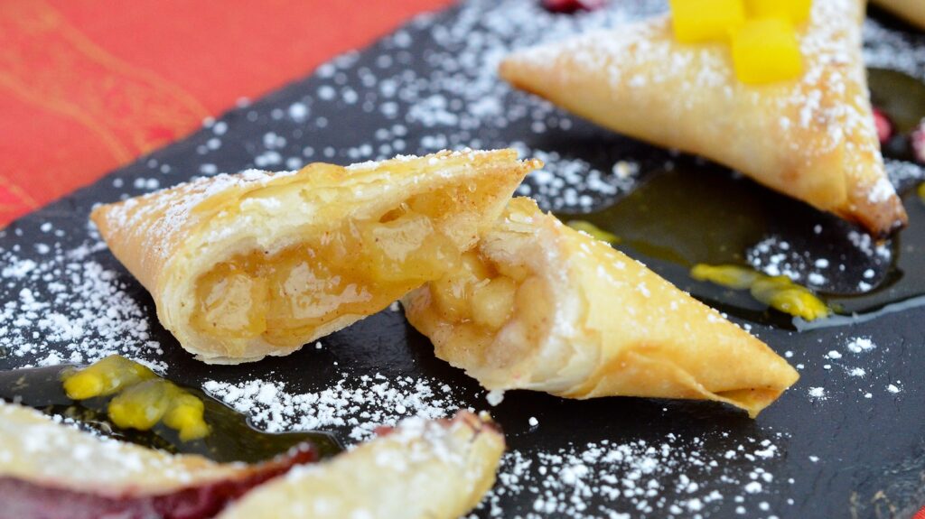 a black plate topped with pastries covered in powdered sugar