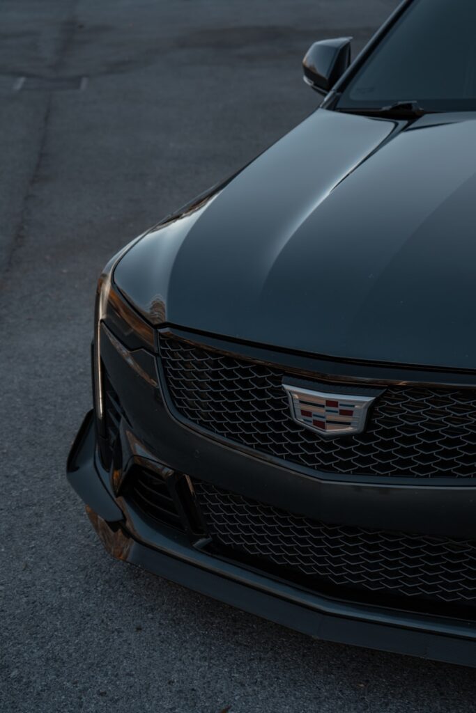 The front end of a black car parked in a parking lot