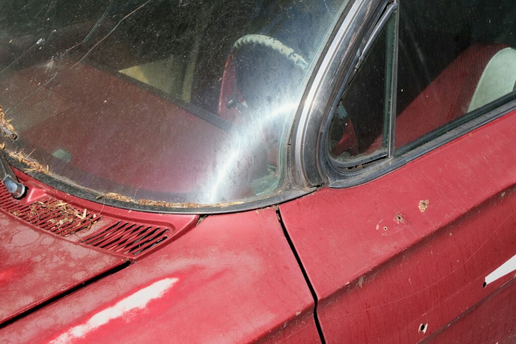 Close-up of a weathered red vintage car interior.